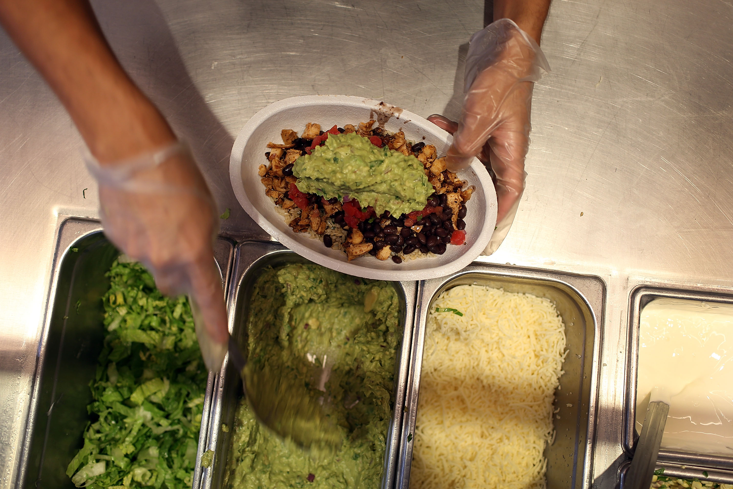 MIAMI, FL - APRIL 27: Chipotle restaurant workers fill orders for customers on the day that the company announced it will only use non-GMO ingredients in its food on April 27, 2015 in Miami, Florida. The company announced, that the Denver-based chain would not use the GMO